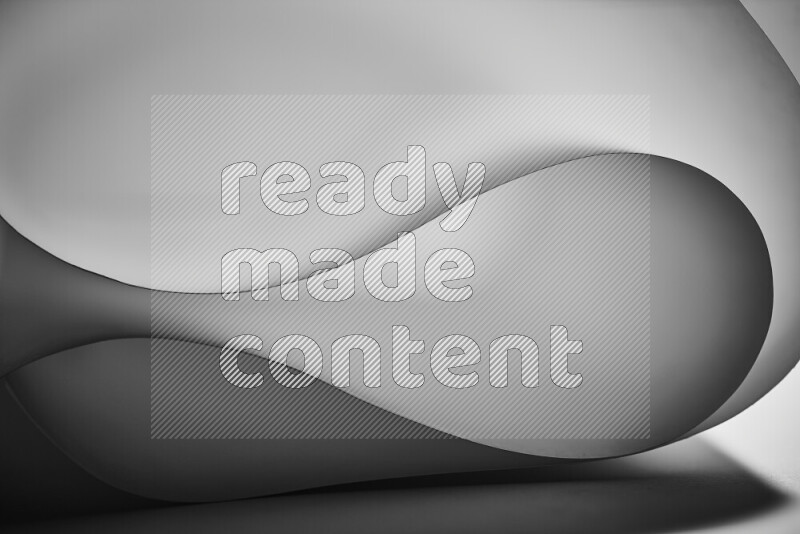 An abstract art piece displaying smooth curves in grey gradients created by colored light