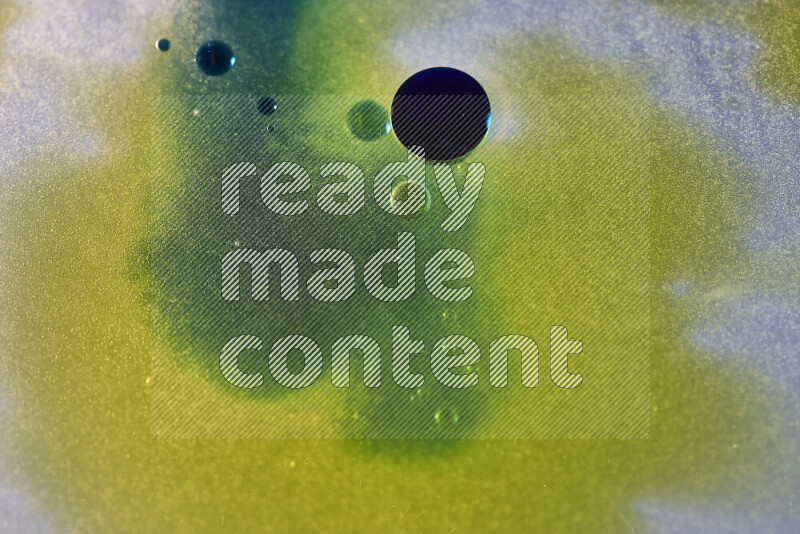 لقطات مقربة لقطرات ألوان مائية صفراء وزرقاء وخضراء على سطح الزيت على خلفية بيضاء