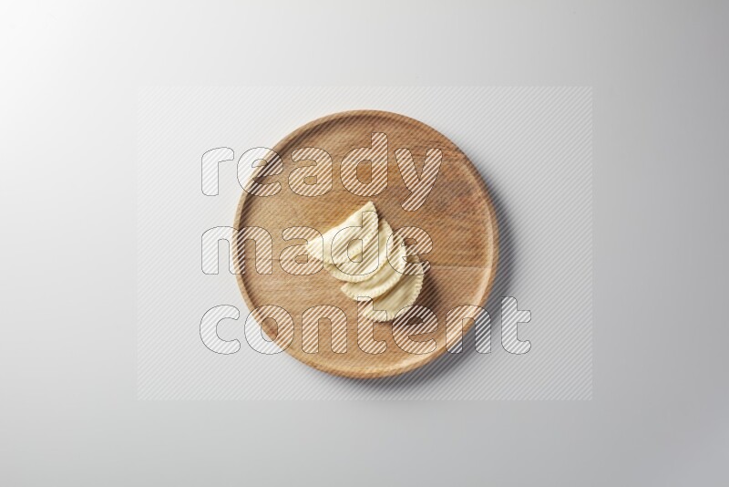 Four Sambosas on a wooden round plate on a white background