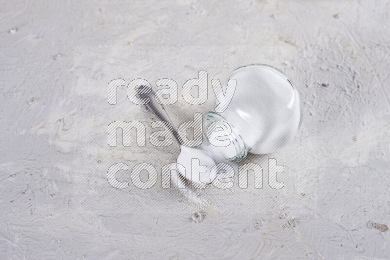 A glass jar full of fine table salt on white background