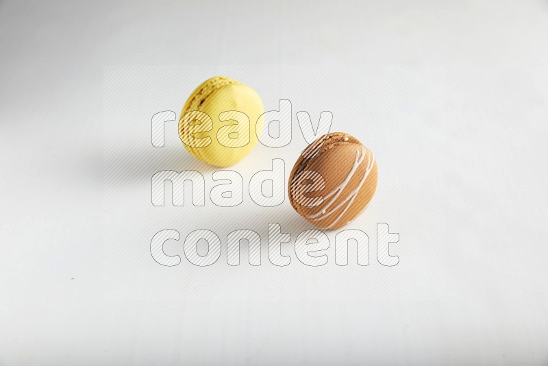 45º Shot of of two assorted Brown Irish Cream, and Yellow Lemon macarons on white background