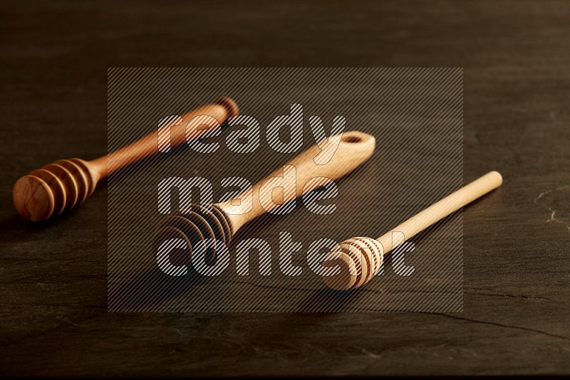 Wooden honey dipper on black slate background
