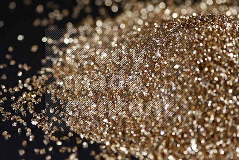 Gold shimmering fragments of glass scattered on a black background