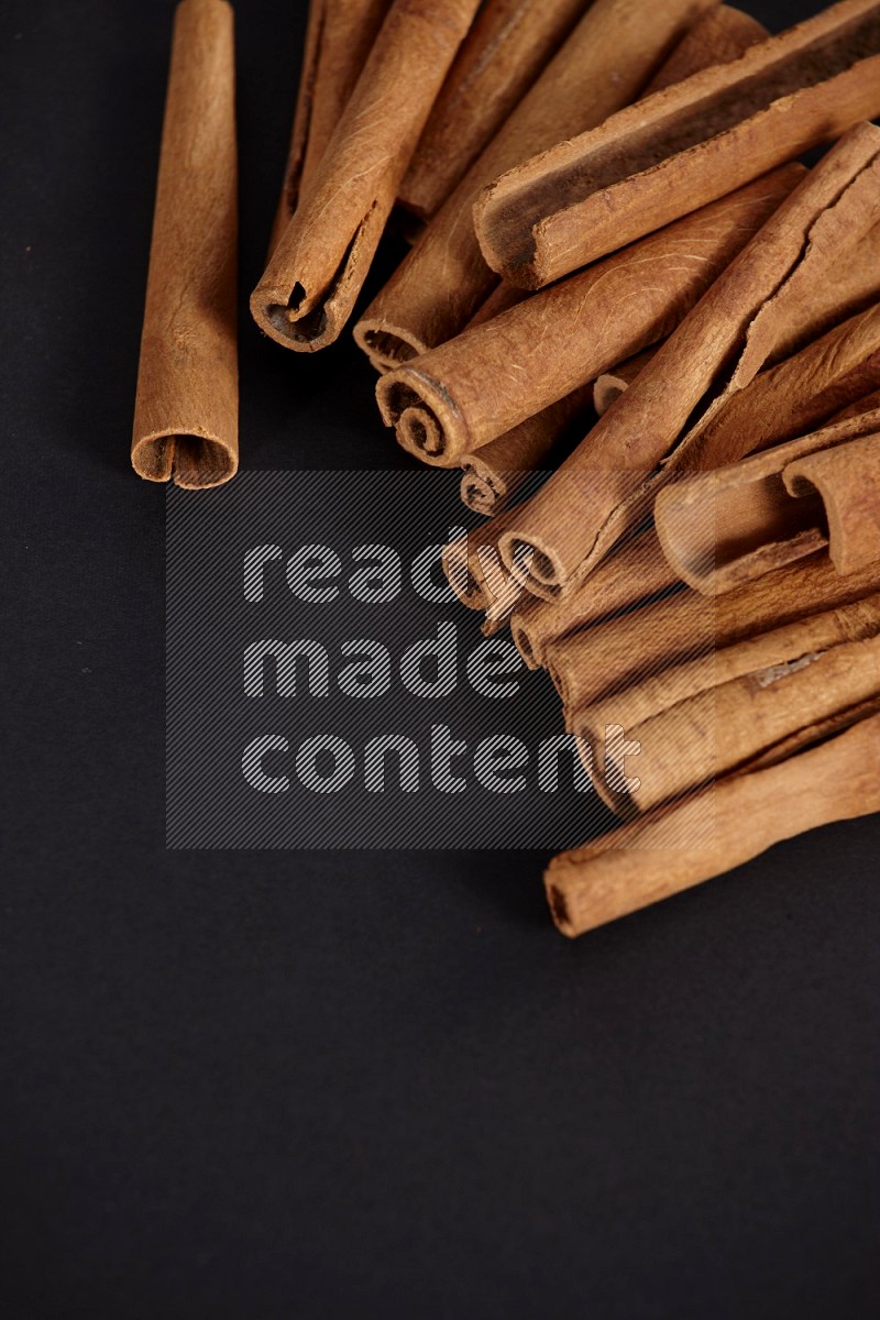 Cinnamon sticks stacked on black flooring