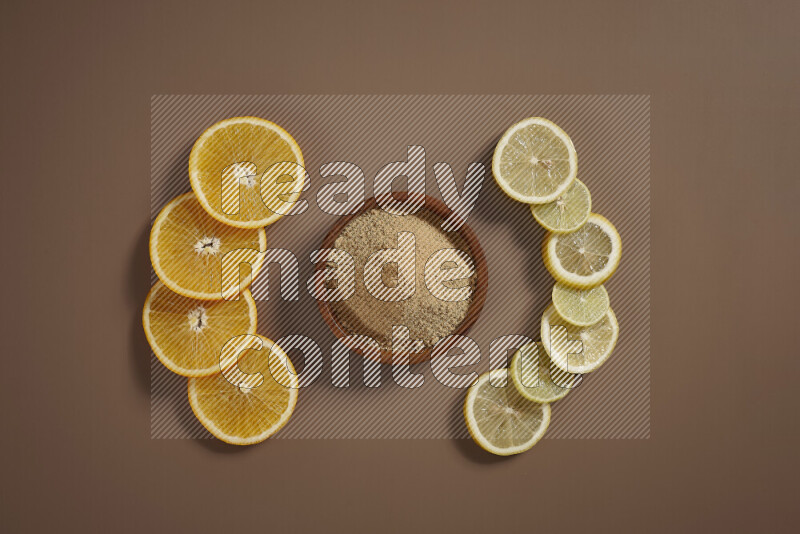 Two bowls full of honey and ground ginger with some of citrus fruits such as lemon and orange on a beige background