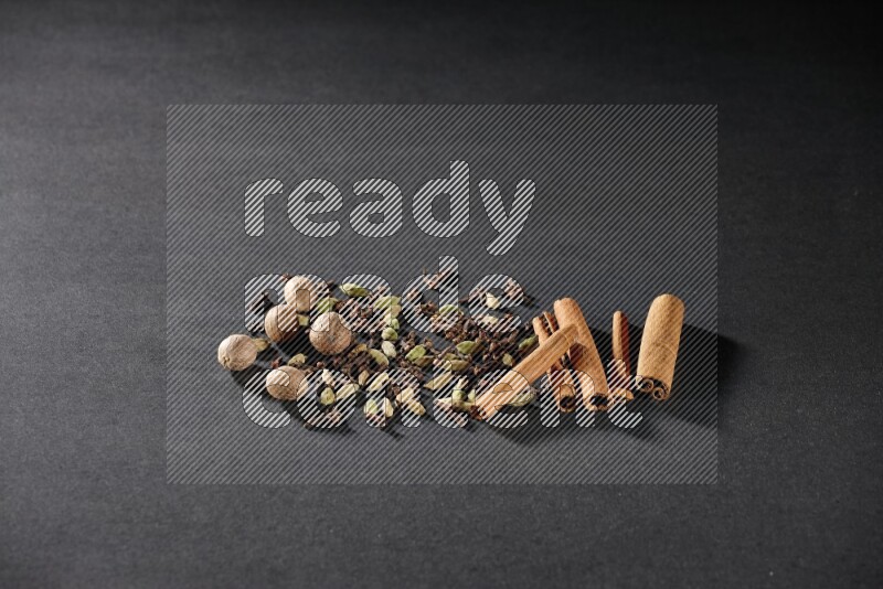 Cardamom, cloves, nutmeg and cinnamon sticks on black flooring