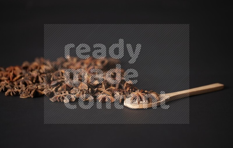 Star Anise in a wooden spoon and spreading on a black flooring