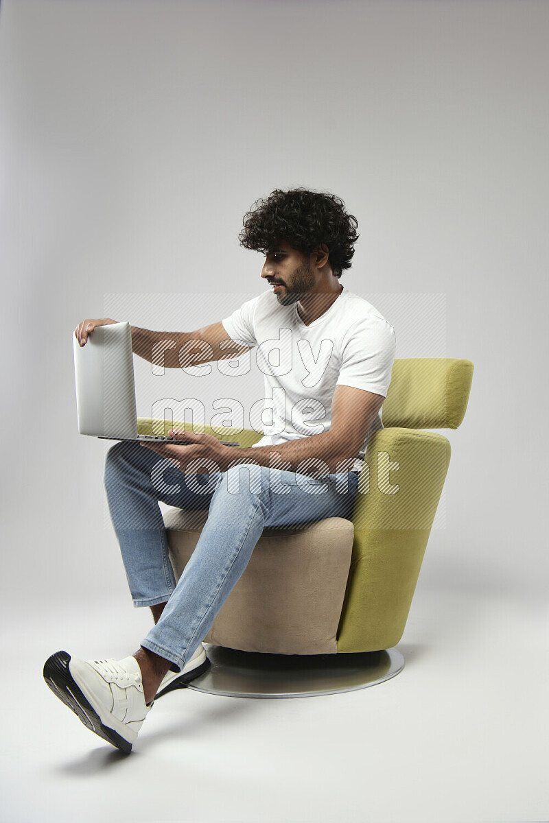 A man wearing casual sitting on a chair working on a laptop on white background