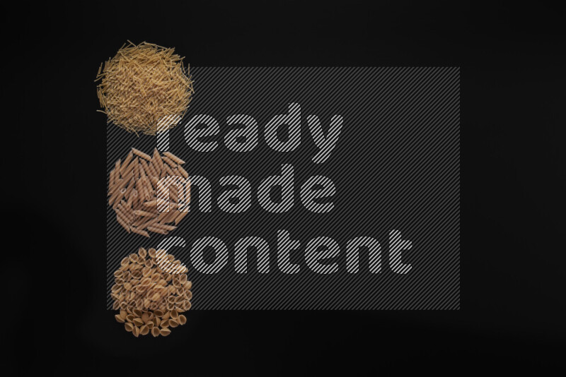 Different pasta types in 3 bunches on black background