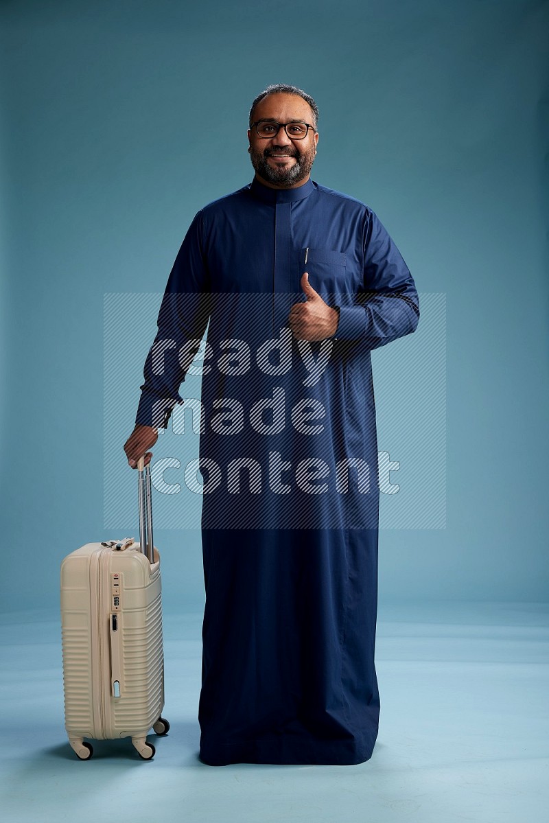 Saudi Man without shimag Standing pulling travel bag on blue background