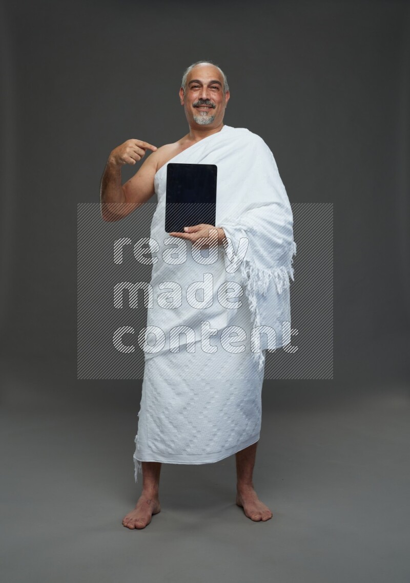 A man wearing Ehram Standing working on tablet on gray background