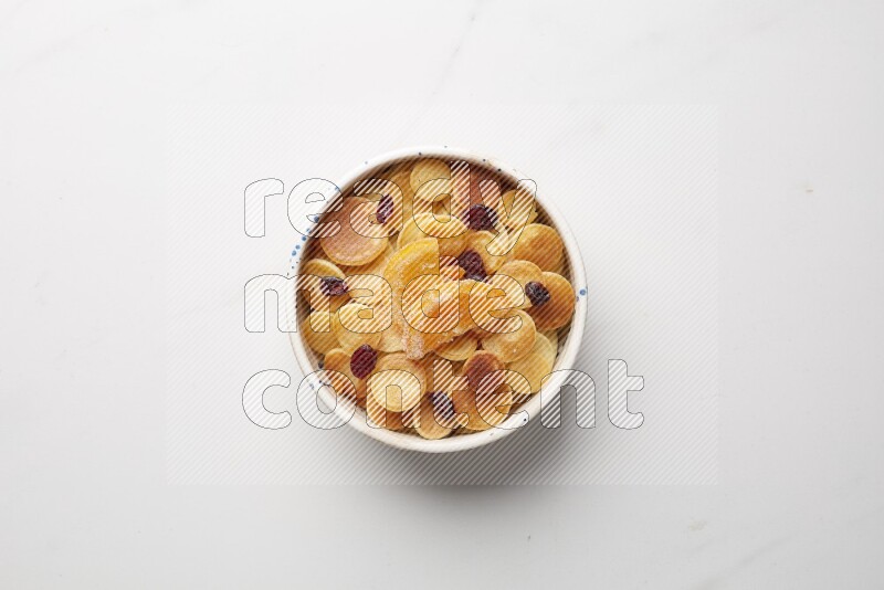 Top-view shot of orange candy cereal pancakes in a round bowl on white background