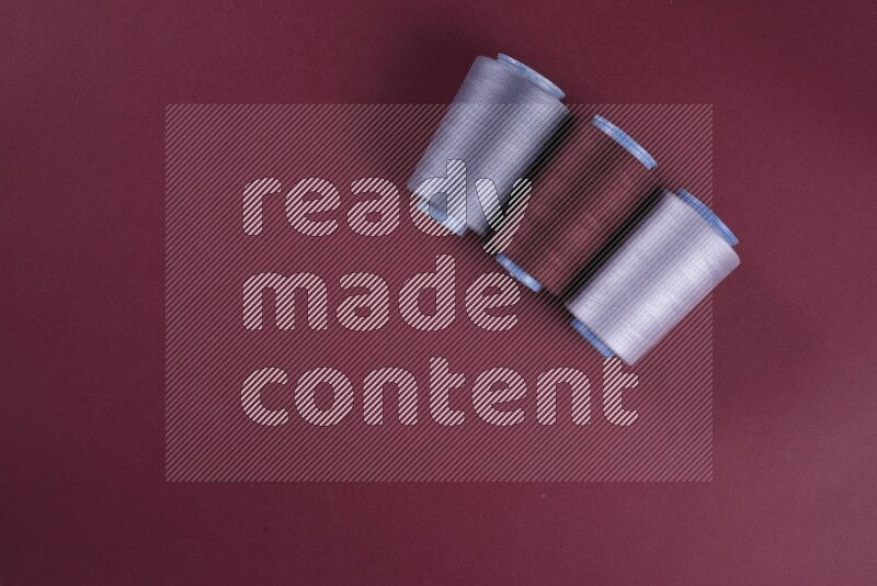 مجموعة من أدوات الخياطة والتفصيل رمادية اللون على خلفية حمراء