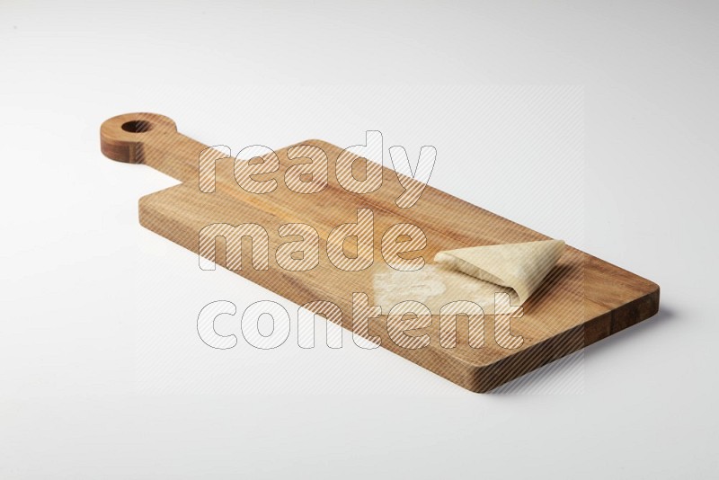 One uncooked samosa on a wooden cutter on a white background