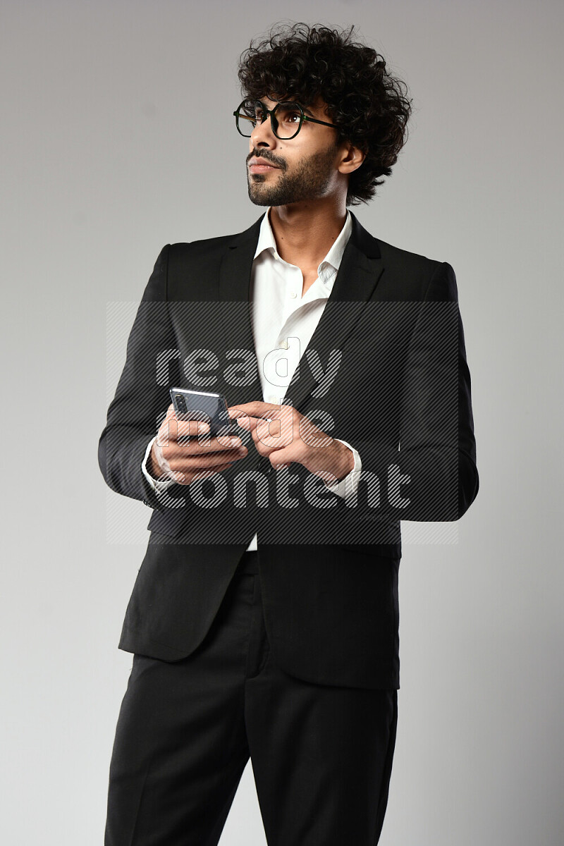 A man wearing formal standing and browsing on the phone on white background