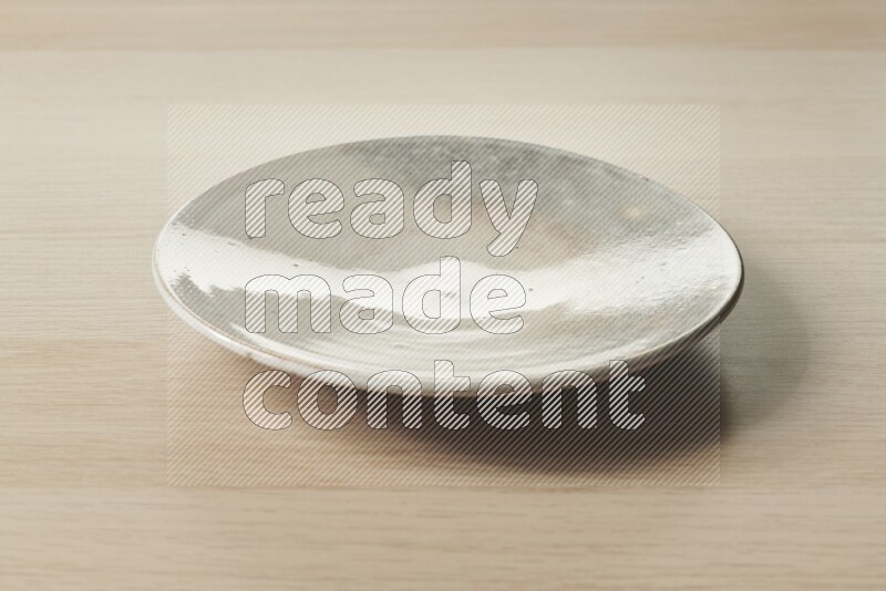 A multicolored pottery plate on light wooden background