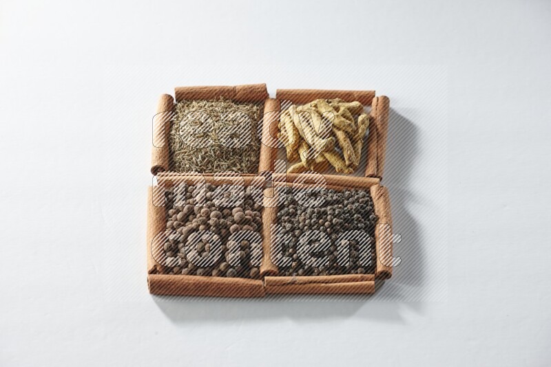 4 squares of cinnamon sticks full of cumin, turmeric fingers, allspice and black pepper on white flooring