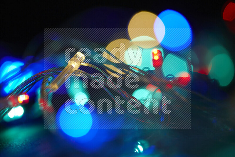 Light bulbs glowing against backdrop of multicolord bokeh