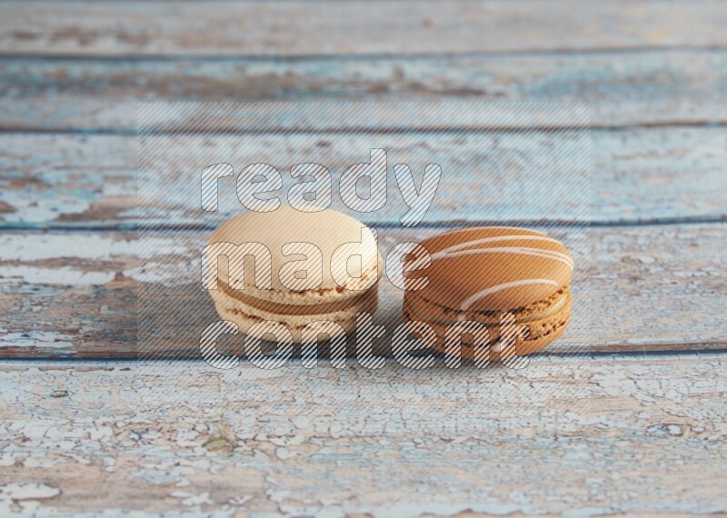 45º Shot of of two assorted Brown Irish Cream, and White Caramel fleur de sel macarons on light blue background