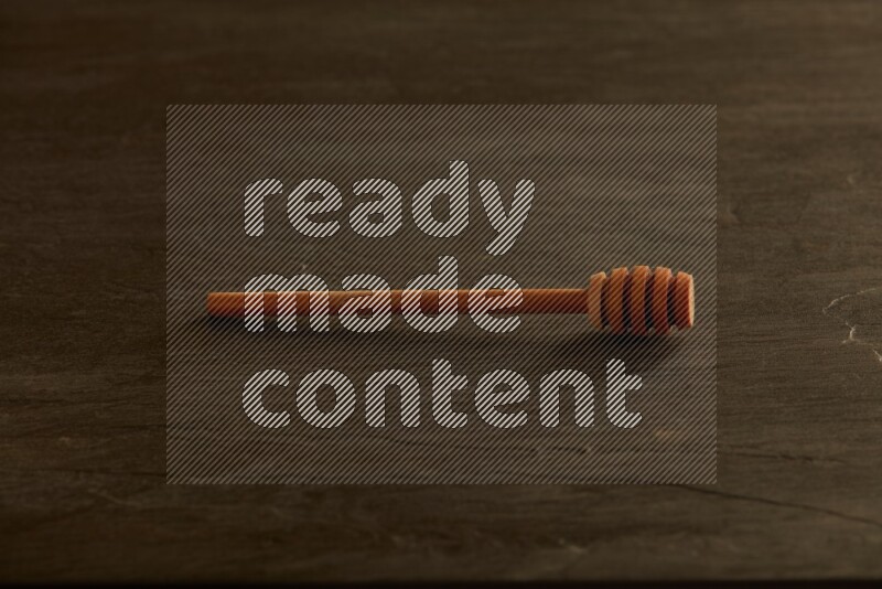 Wooden honey dipper on black slate background
