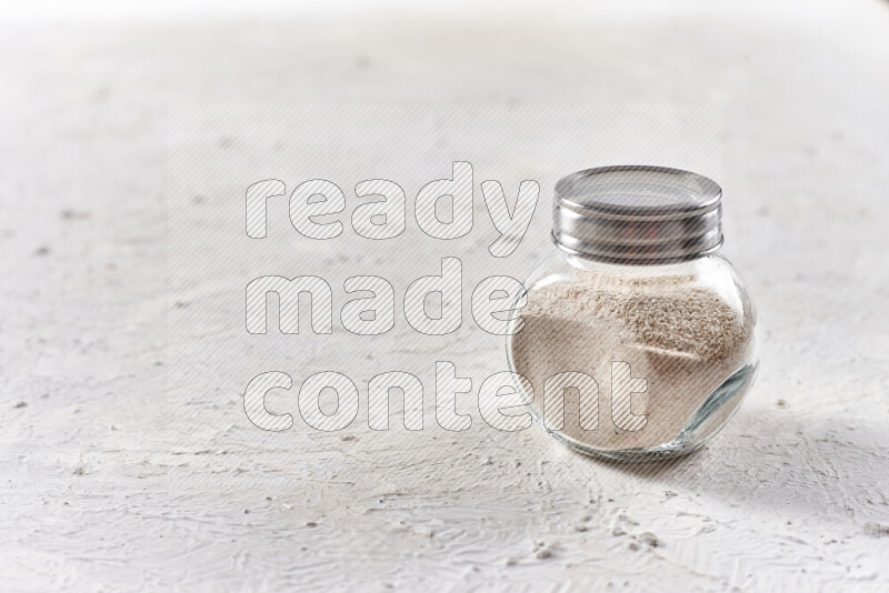 A glass jar full of onion powder on white background