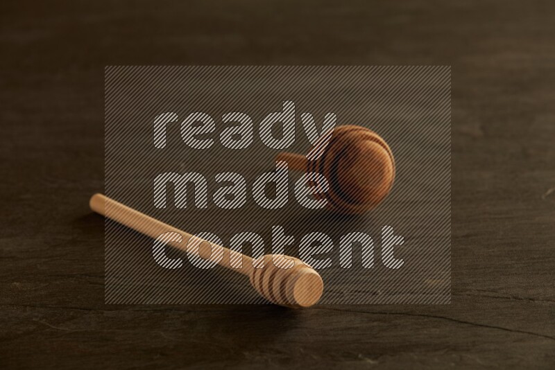 Wooden honey dipper on black slate background