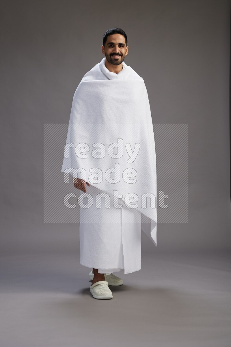 A man wearing Ehram Standing Interacting with the camera on gray background