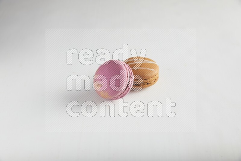 45º Shot of of two assorted Brown Irish Cream, and Purple Strawberry macarons on white background