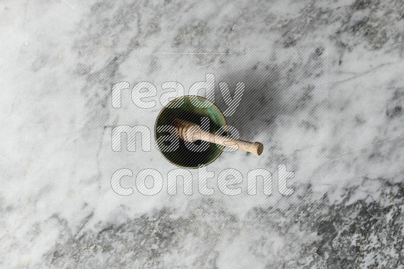 Multicolored Pottery Bowl with wooden honey handle in it, on grey marble flooring, Top View