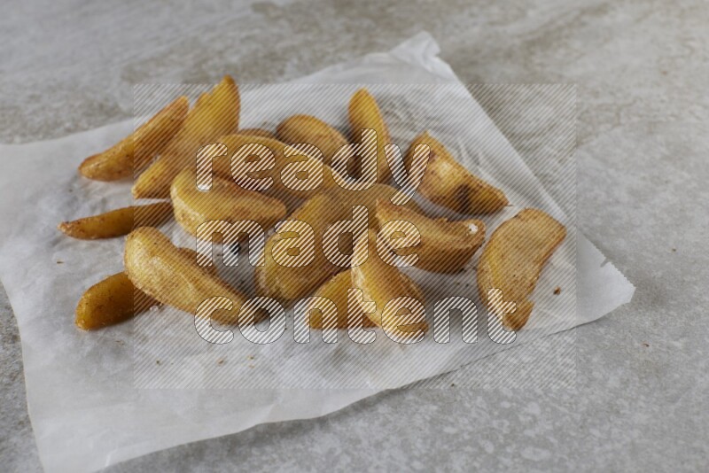 wedges potato on parchment paper on grey textured counter top