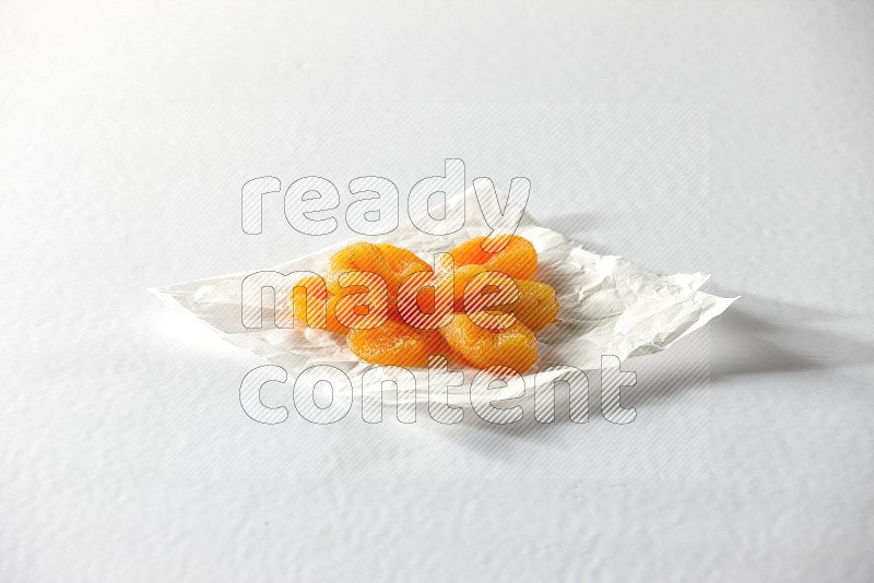 حبات من المشمش المجفف على قطعة من الورق على خلفية بيضاء