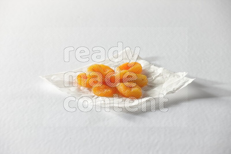Dried apricots on a crumpled piece of paper on a white background in different angles