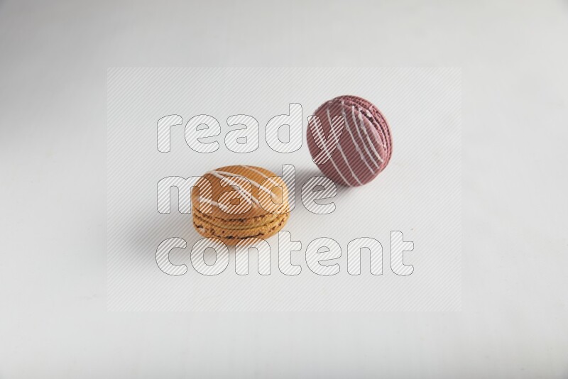 45º Shot of of two assorted Brown Irish Cream, and Red Poppy Flower macarons on white background