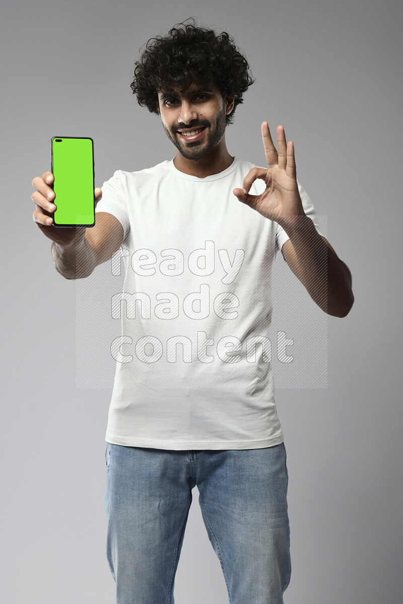 A man wearing casual standing and showing a phone screen on white background
