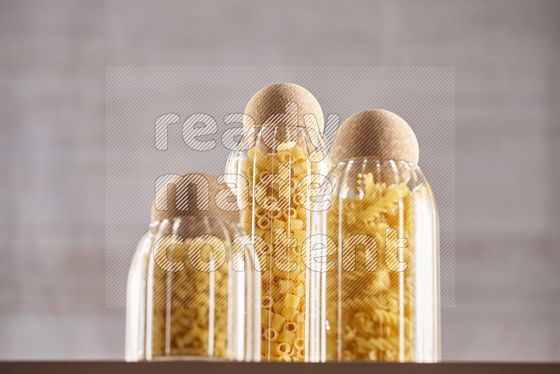 Raw pasta in glass jars on beige background