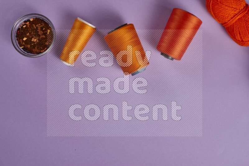 مجموعة من أدوات الخياطة والتفصيل برتقالية اللون على خلفية أرجوانية