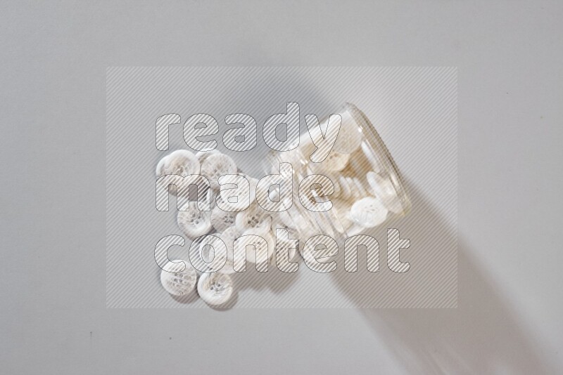 أزرار ملونة في وعاء زجاجي على خلفية رمادية