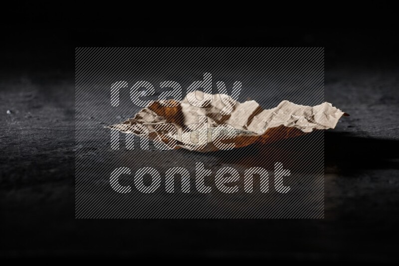 White pepper powder in a crumpled paper on textured black flooring