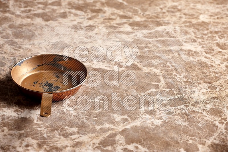 Small Copper Pan on Beige Marble Flooring, 45 degrees