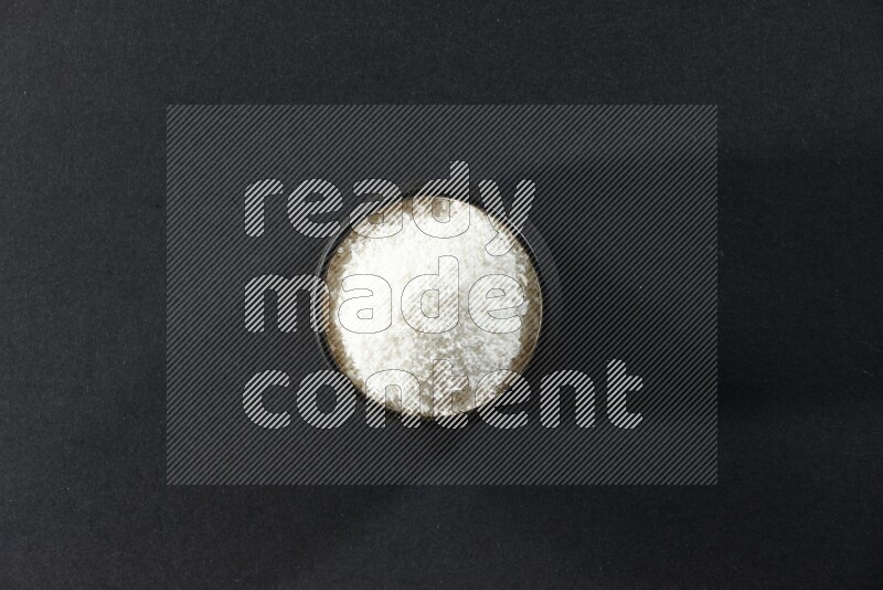 وعاء فخاري أسود ممتلئ بجوز الهند المجفف المبشورعلى خلفية سوداء