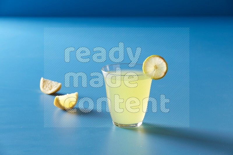 glass of lemon juice with lemon slice  on blue background
