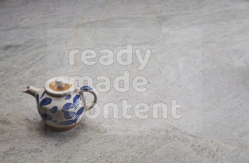 A pottery teapot on grey marble background