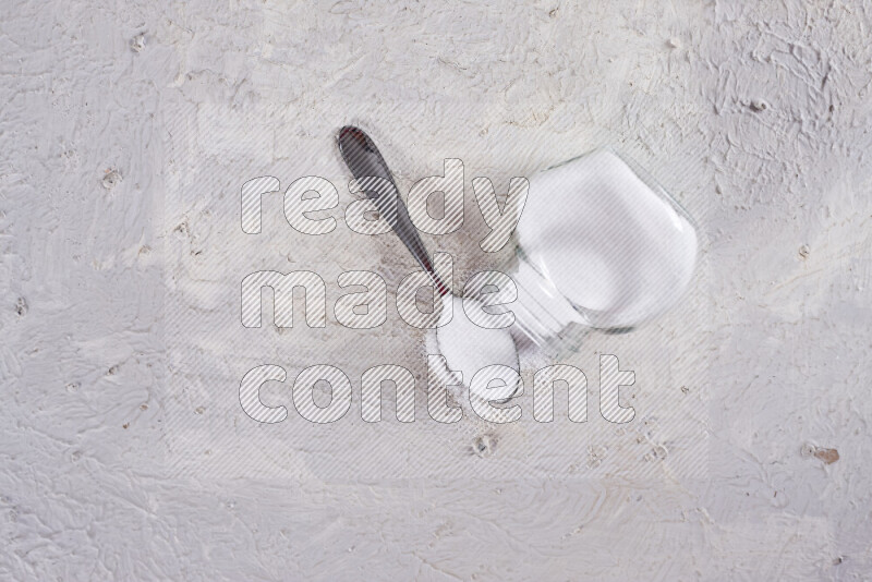 A glass jar full of fine table salt on white background