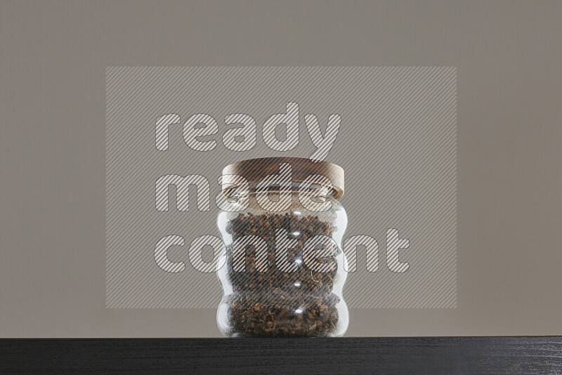 Dried basil in a glass jar on black background