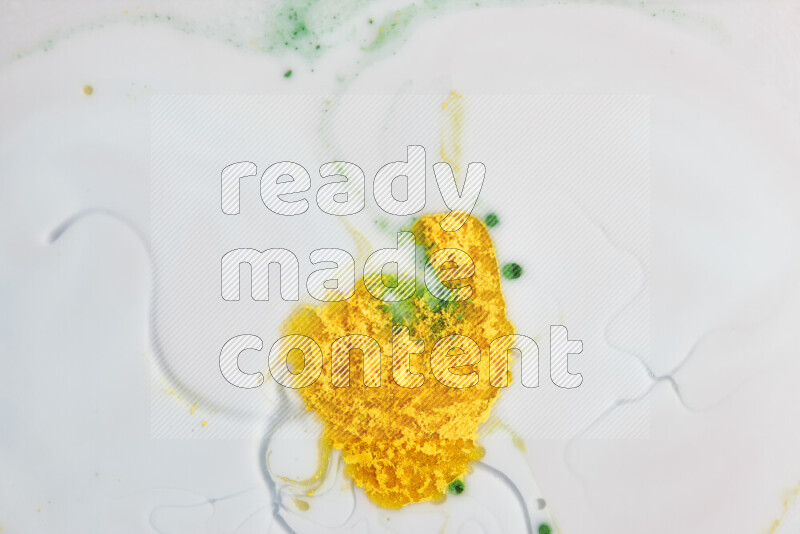 The image captures a splatter of yellow and green paint over a white backdrop