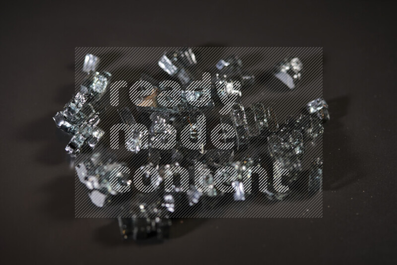 Transparent black fragments of glass scattered on a black background