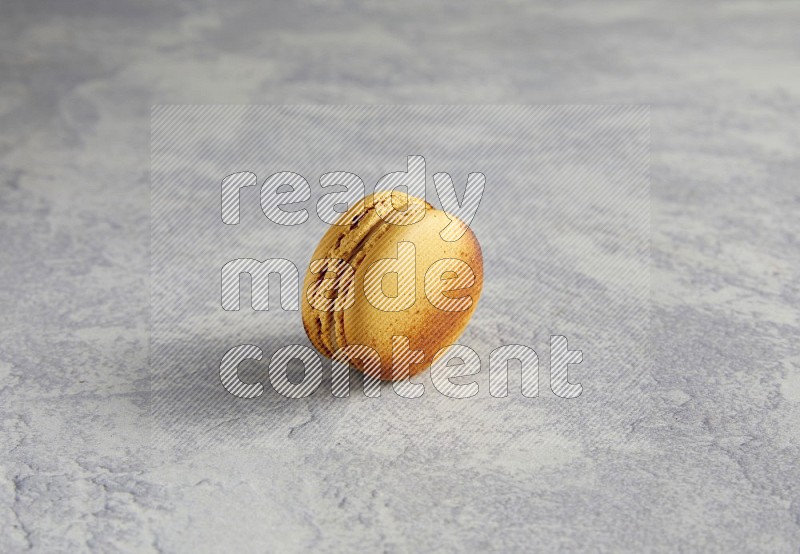 45º Shot of Yellow Crème Brulée macaron on white marble