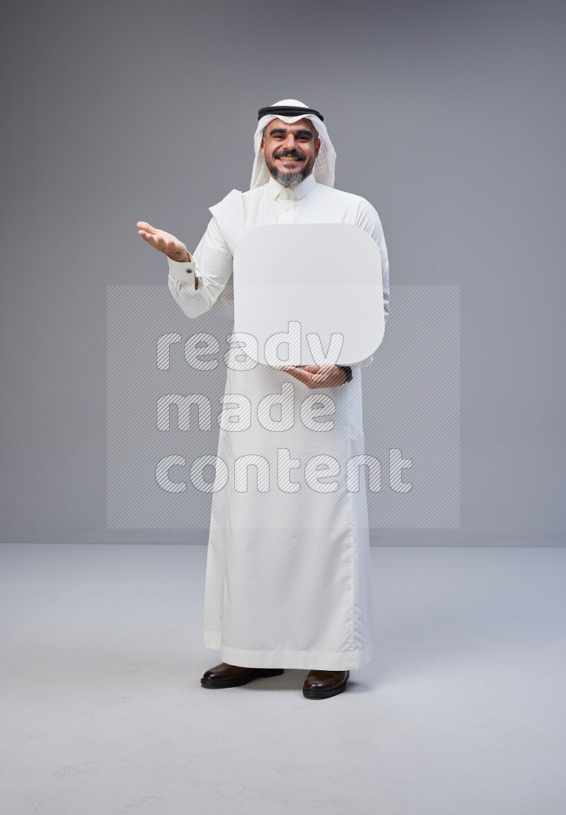 Saudi man Wearing Thob and white Shomag standing holding social media sign on Gray background