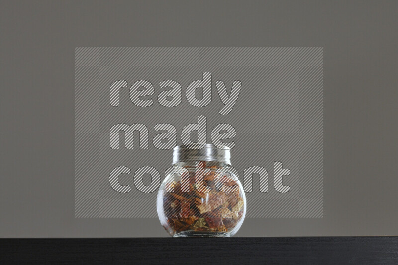 Chili pepper in a glass jar on black background