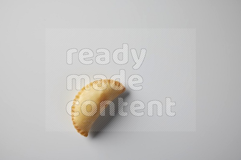 One fried sambosa from a top angle on a white background